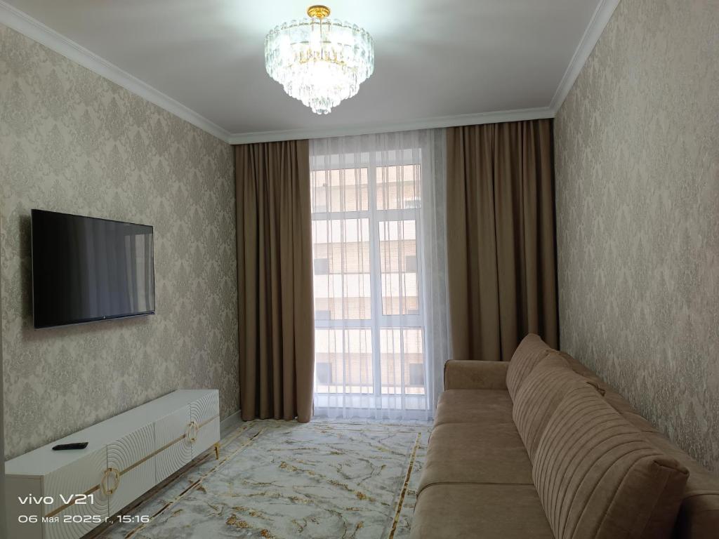 Una sala de estar con un sofá y un televisor. en Мадрид, en Astana