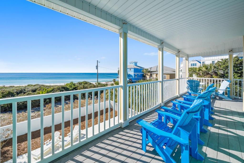 a row of blue chairs on a porch with the beach at Surfer Dog l Beachfront Pool l Includes Beach Chairs and Bikes in Inlet Beach