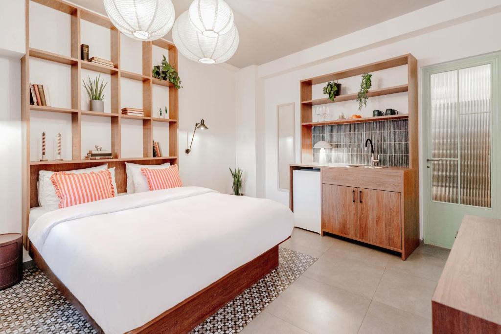 Dogpound Hotel في أثينا: غرفة نوم بها سرير أبيض كبير ومطبخ