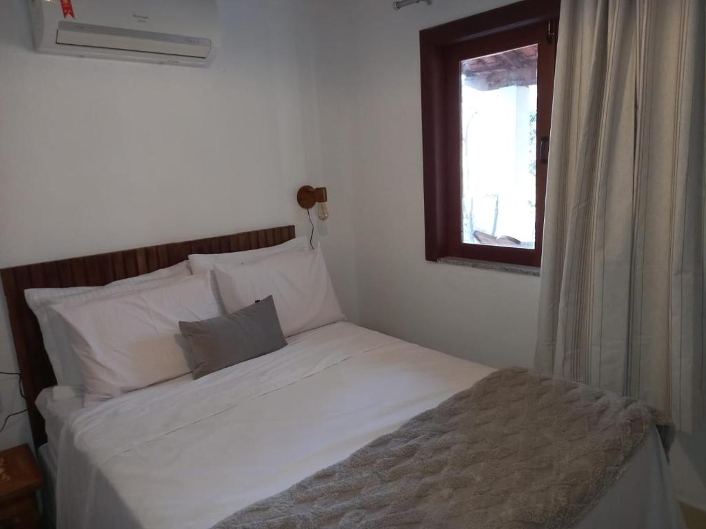 een bed met witte lakens en een raam in een kamer bij Chalé Colibri in Palmeiras