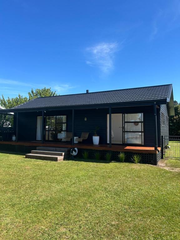 a black house with a large yard at Coastal Escape - Cooks Beach in Cooks Beach