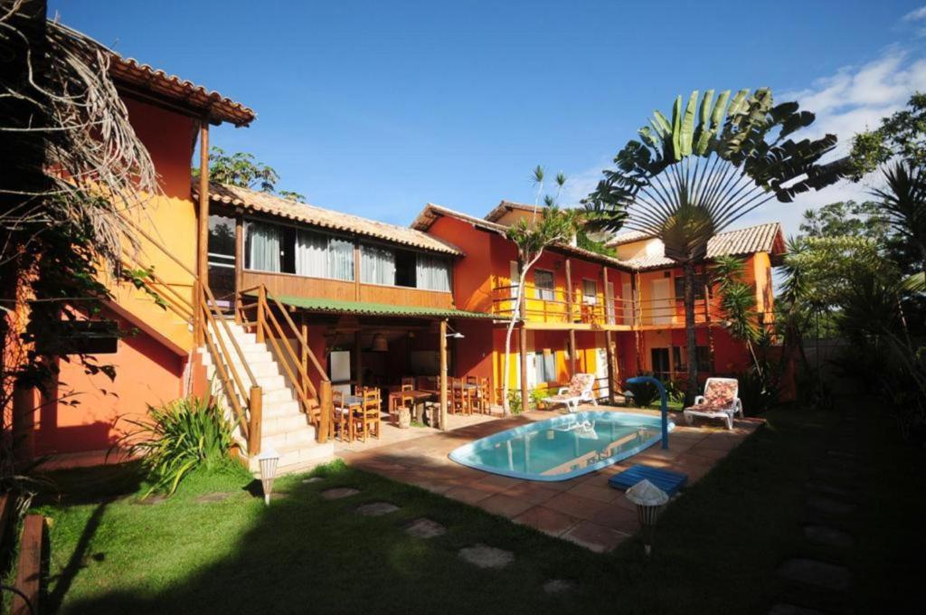 a house with a swimming pool in front of it at Mandacaru Pousada in Porto Seguro