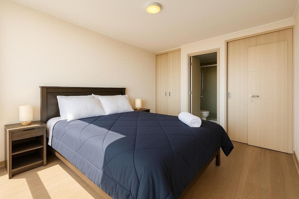 Un dormitorio con una cama grande con una manta azul. en la cuidad en las alturas, en Concepción