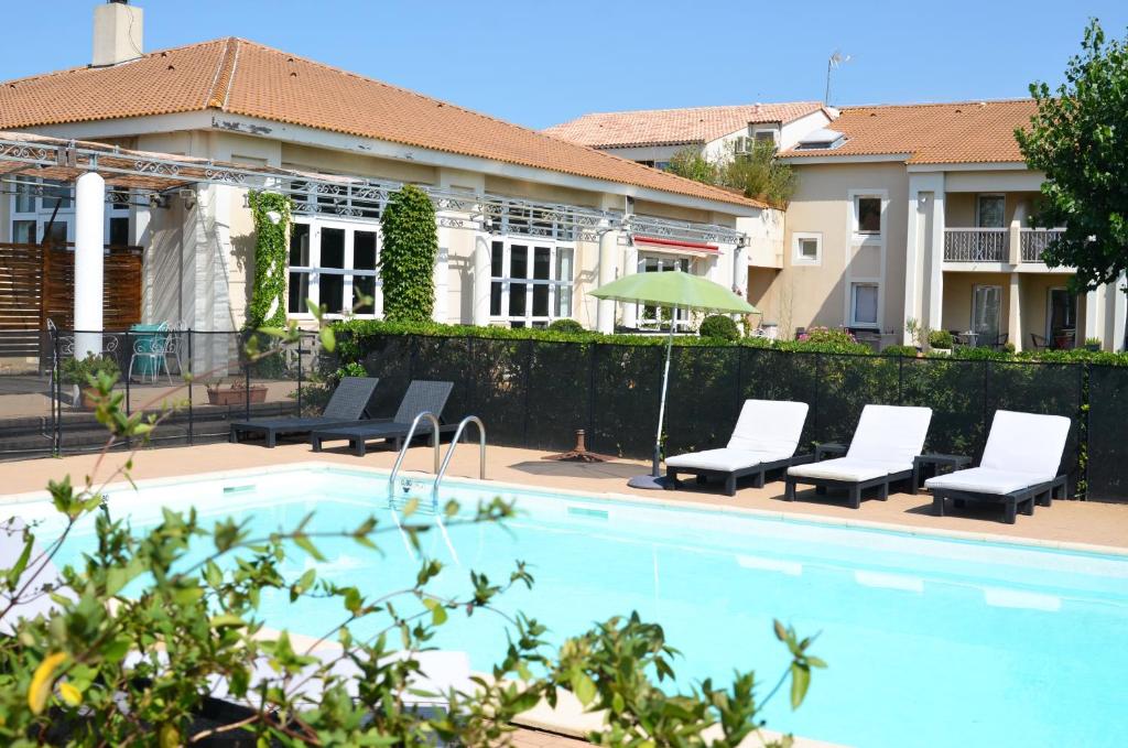 uma piscina com espreguiçadeiras ao lado de uma casa em Hôtel le Mas des Ponts d'Arles em Arles