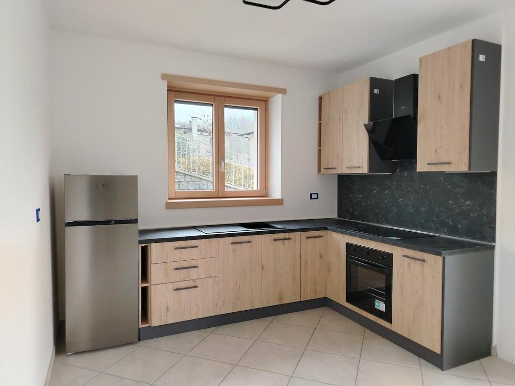 une cuisine avec des armoires en bois et un réfrigérateur en acier inoxydable dans l'établissement Appartamento da Nonna Anna, à Montagna in Valtellina