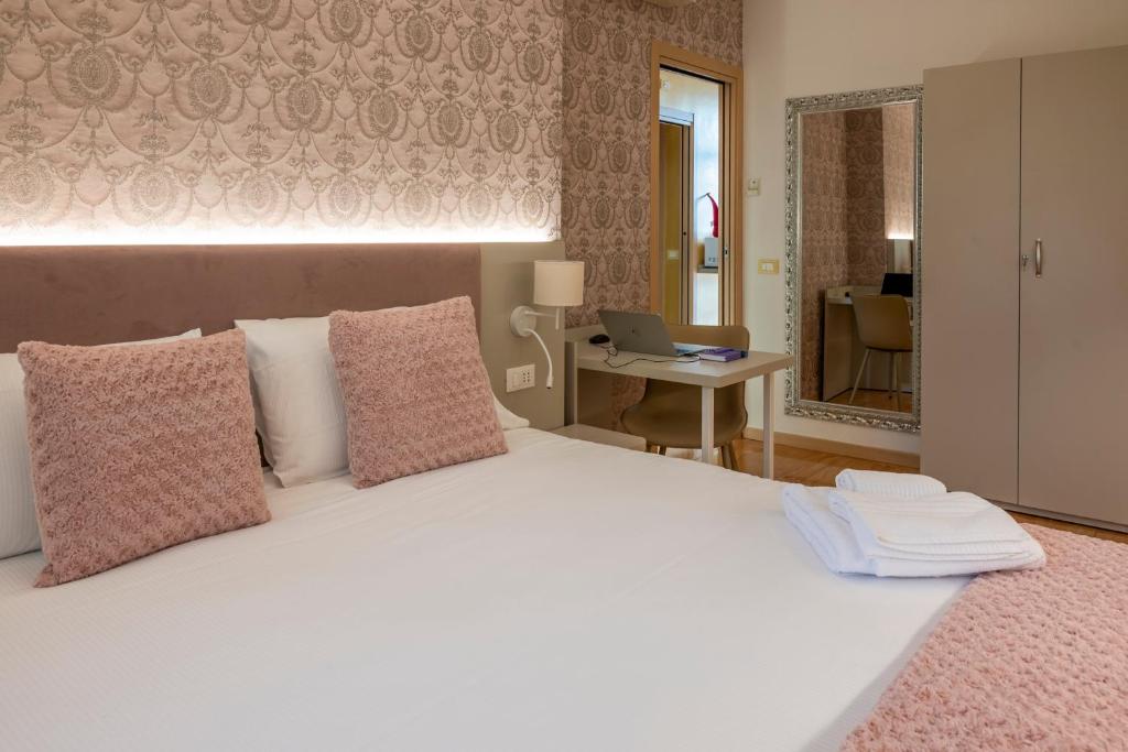 a bedroom with a large white bed and a desk with a laptop at Appartamenti S Onofrio Rho in Rho