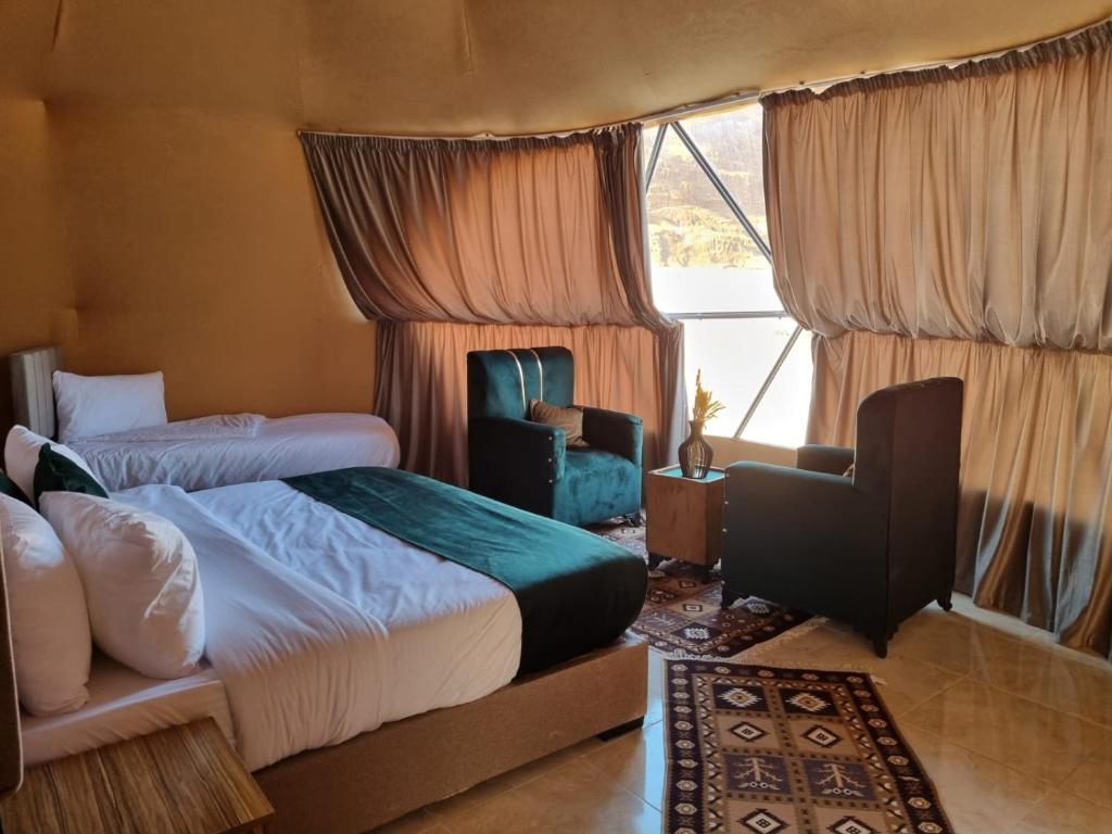 a bedroom with two beds and a chair and a window at Kylie magic camp in Wadi Rum