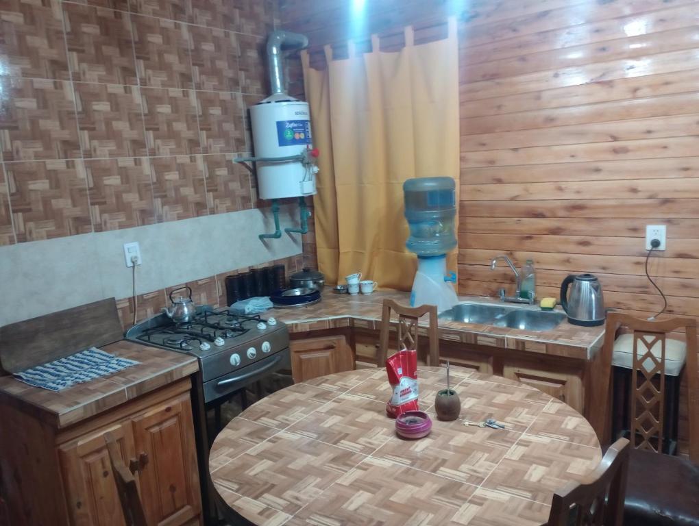 - une cuisine avec une table, une cuisinière et un évier dans l'établissement Cabaña el amanecer, à Dolores