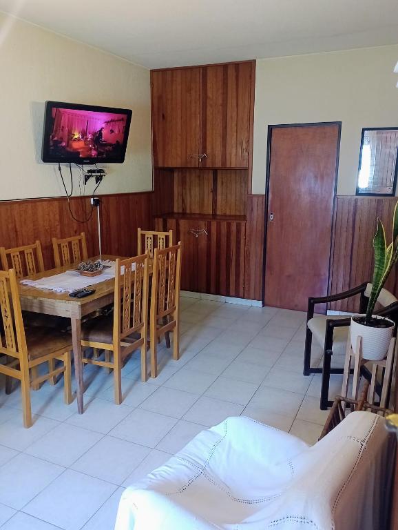 een eetkamer met een tafel, stoelen en een televisie bij Nono110 in Villa Gesell