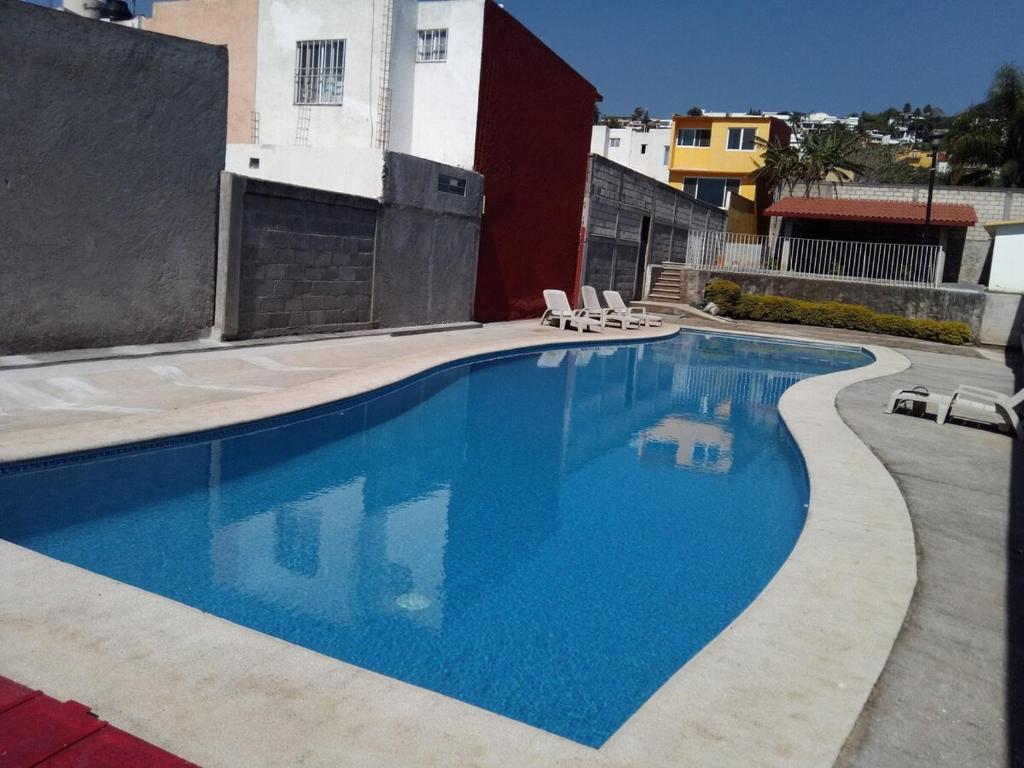 a swimming pool with two chairs and a building at Casa en fraccionamiento en Ahuatepec con alberca, cancha y cerca de Tepoztlán 