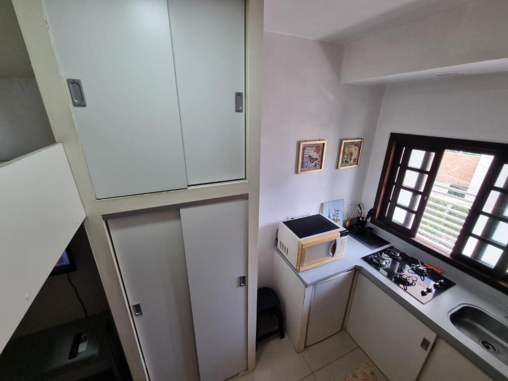 uma pequena cozinha com pia e micro-ondas em Kitnet Minimalista Mezanino em São Paulo