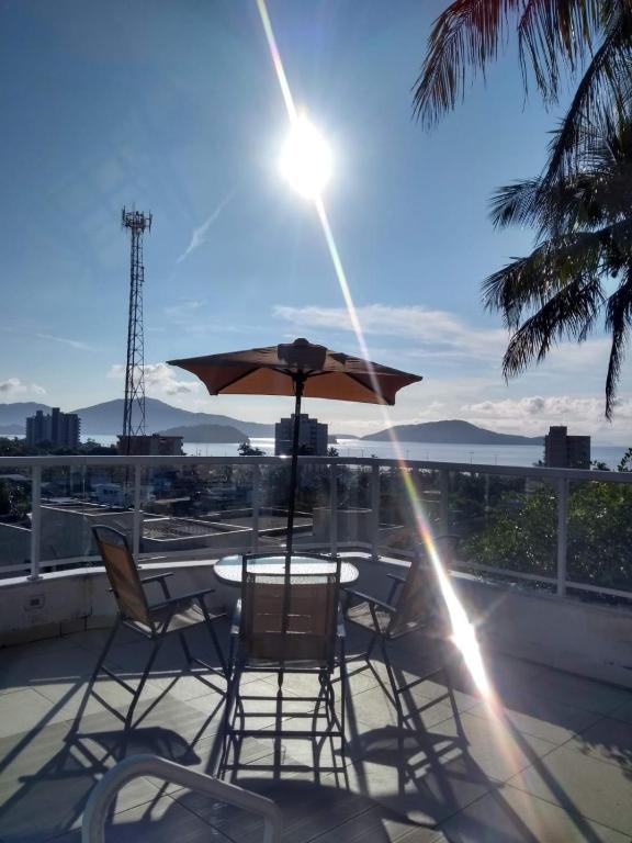 a table and chairs with an umbrella on a balcony at Casa de Alto Padrão Piscina e Linda Vista para o Mar in Caraguatatuba