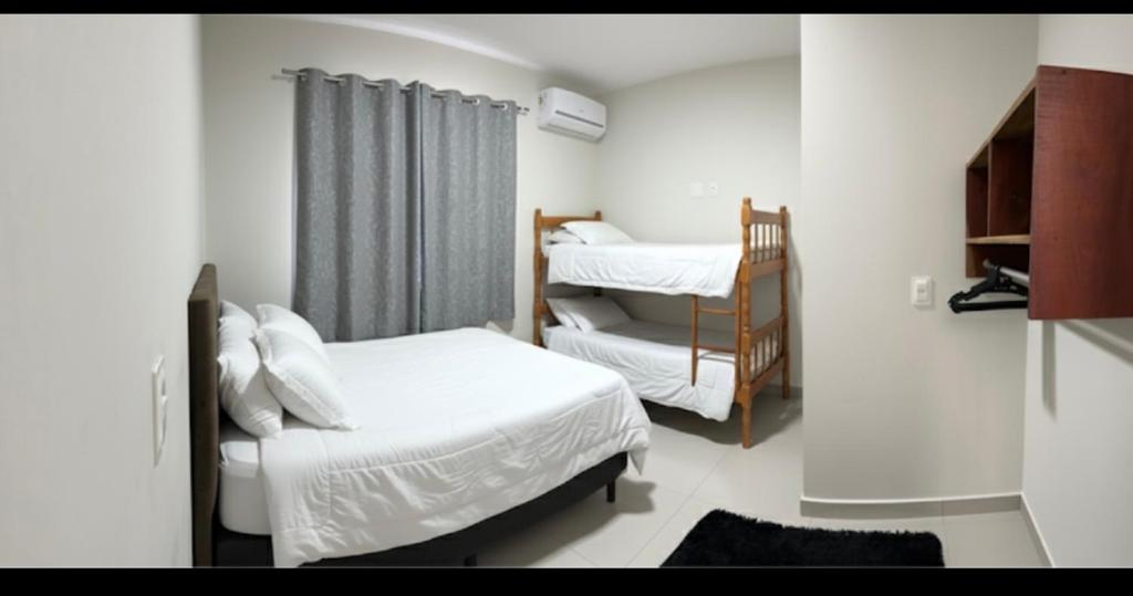 ein kleines Schlafzimmer mit zwei Betten und einem Fenster in der Unterkunft Pousada Aloha Pinheira in Palhoça