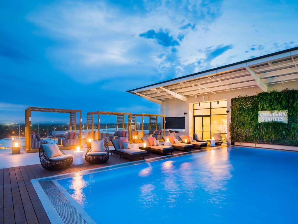 Una piscina de hotel con tumbonas y televisión. en The William Inglis Mgallery, en Warwick Farm