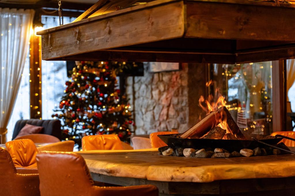 a fireplace in a room with a christmas tree at Maar Hotel Brezovice in Prevallë