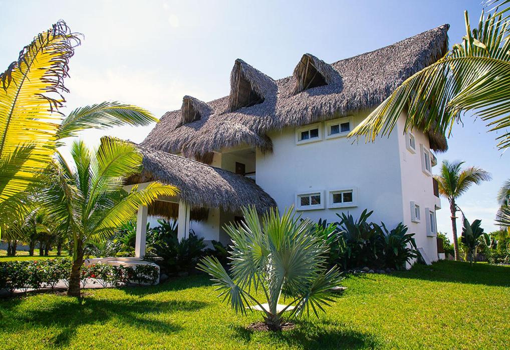 a large white building with a thatched roof at Hotel Dos Mundos Monterrico - Pacific Resort in Taxisco