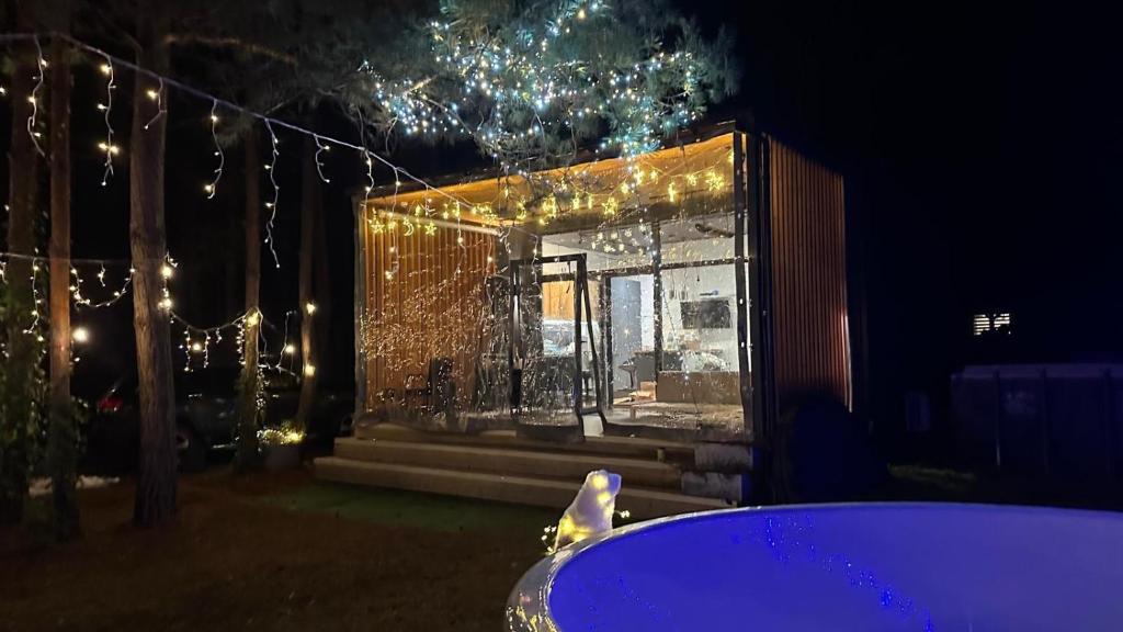 a house with christmas lights in a yard with a tub at LEŚNY LUZ domek z jacuzzi w lesie nad jeziorem, duży taras, ognisko, gril, basen in Chańcza