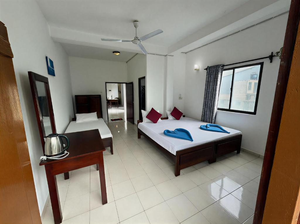 a bedroom with two beds and a desk in it at Athula Beach Front Hotel Hikkaduwa in Hikkaduwa