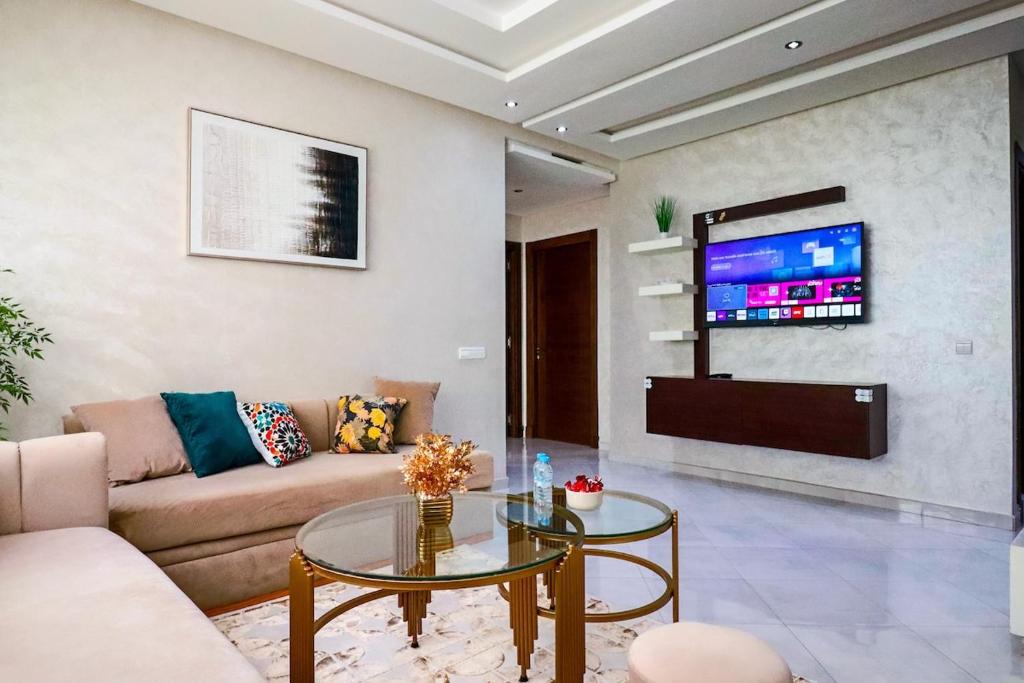 a living room with a couch and a table and a tv at L'Etincelle 2 chambres à deux pas de la Gare in Kenitra