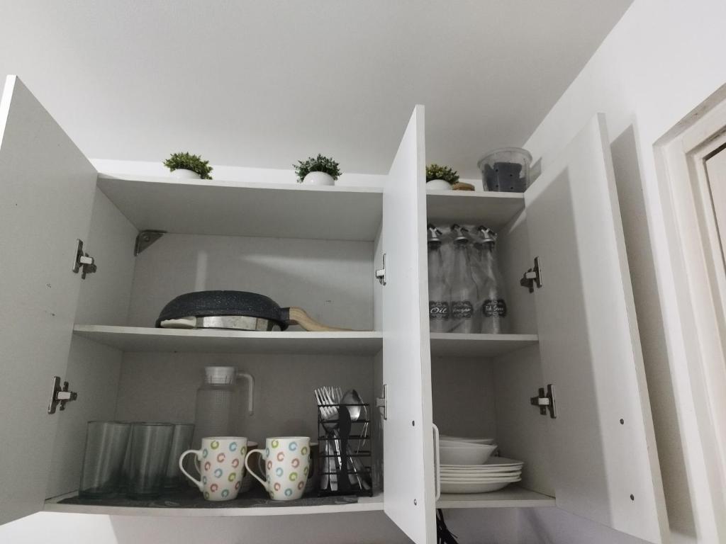 a white cupboard with cups and mugs in it at The Happy Home at Smdc Cool Suites Wind Residences in Tagaytay