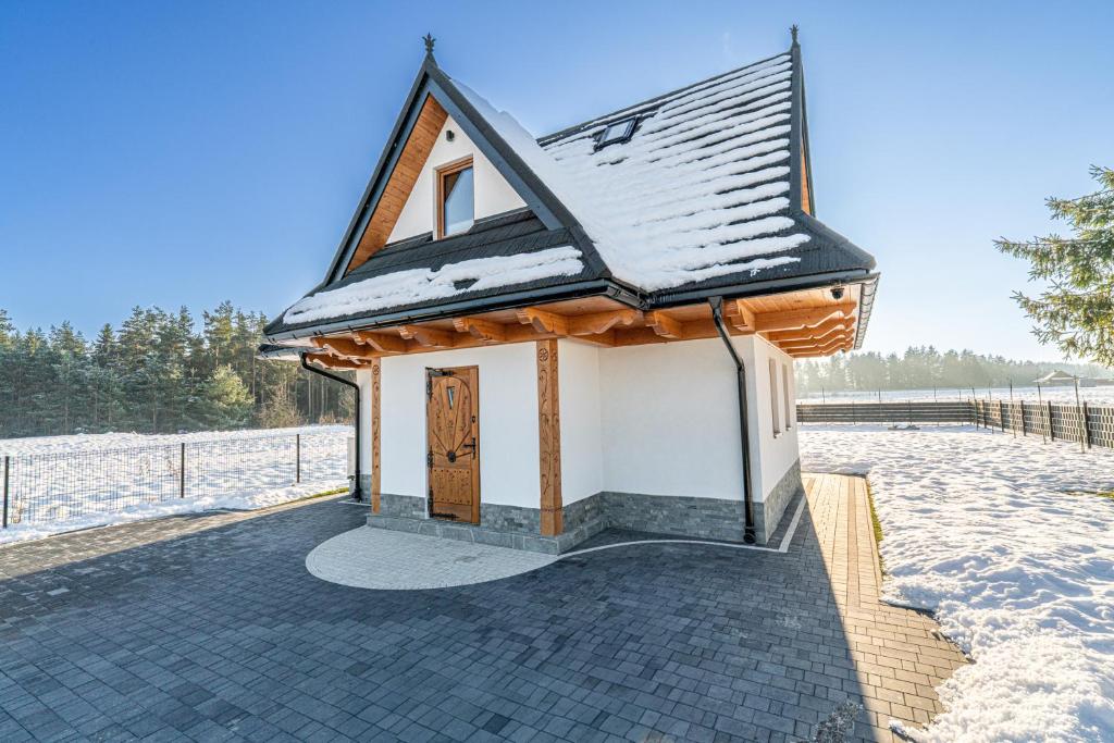 a small house with a snow covered roof at Chatka Marysi - Domek z prywatnym SPA in Dębno