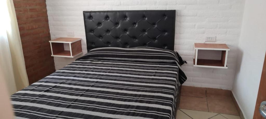 a bed with a black headboard in a room at Lo de Vlady in Mina Clavero