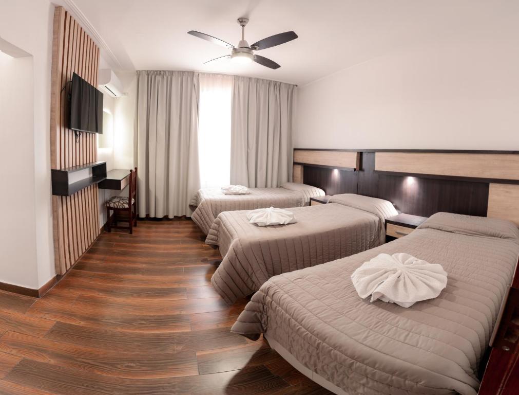 a hotel room with three beds and a ceiling fan at Grand Hotel Principado in Termas de Río Hondo