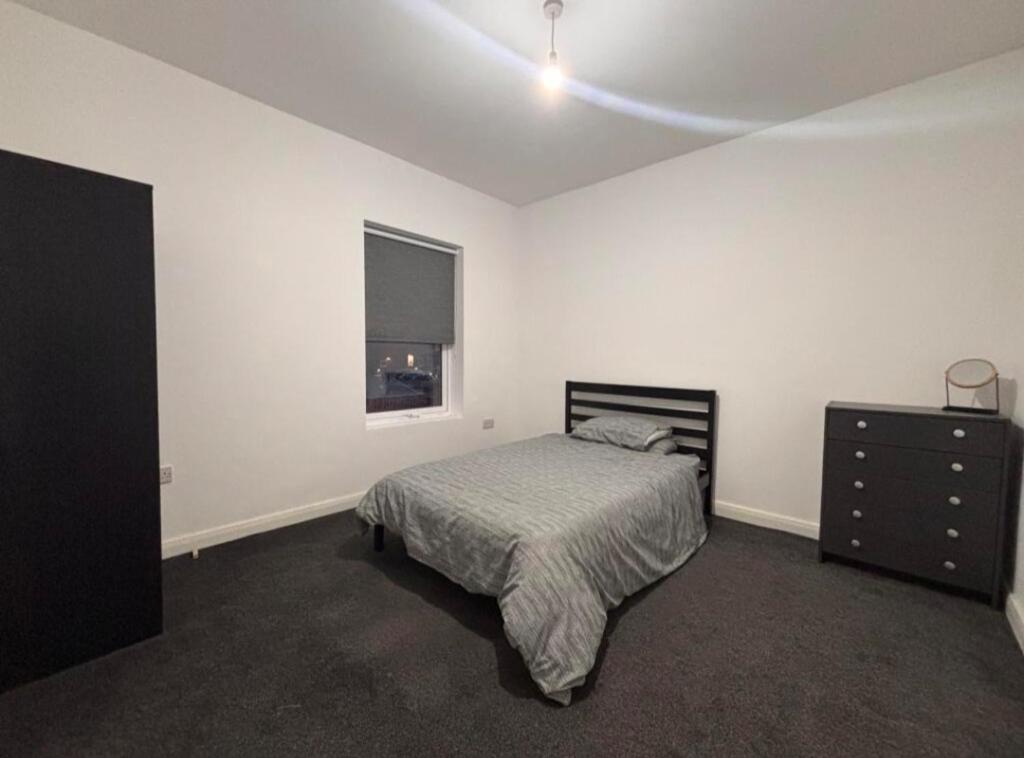a bedroom with a bed and a dresser and a window at Near Manor Hospital Free Wifi in Walsall