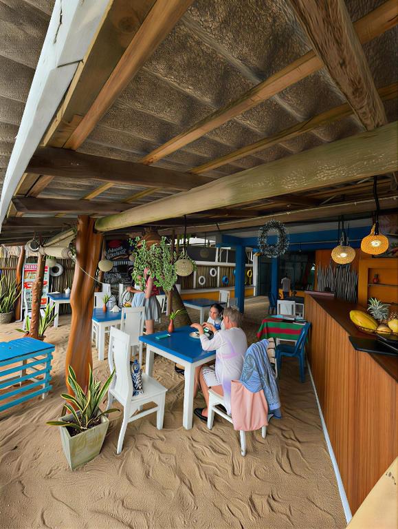 a restaurant with people sitting at tables in the sand at Athula Beach Front Hotel Hikkaduwa in Hikkaduwa