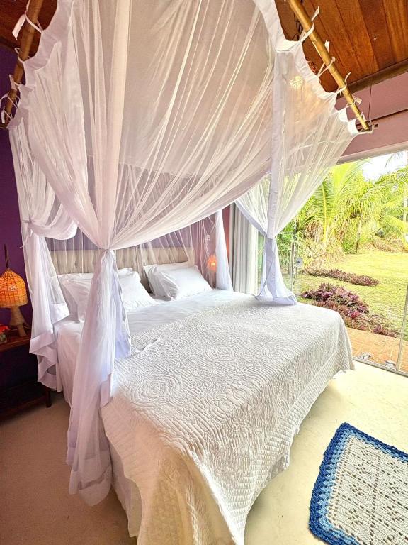 a bedroom with two beds with white mosquito netting at Vila BeiradeiRô - Taipu de Fora in Taipu