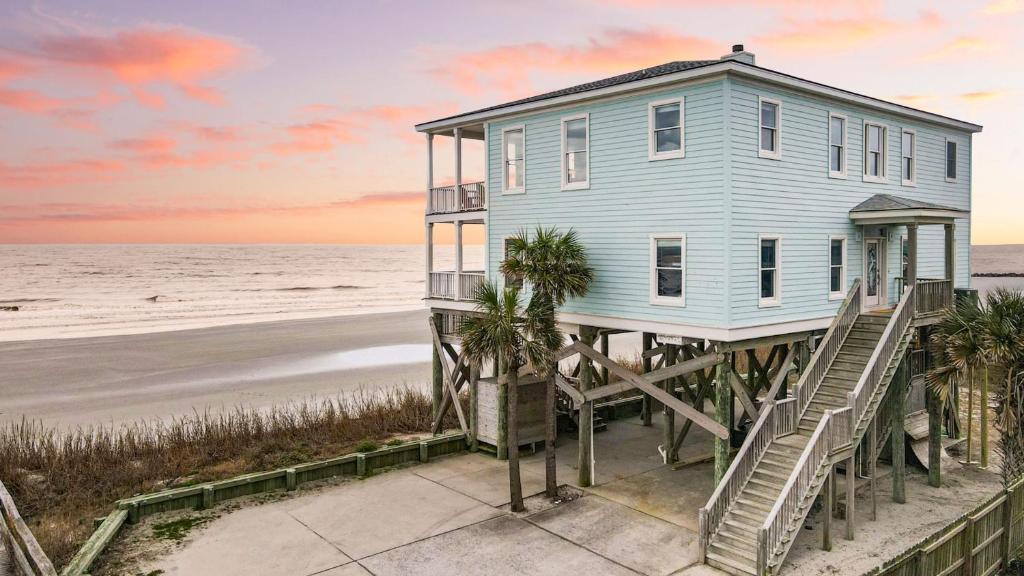 a blue house on a pier next to the beach at Poseidon By AvantStay On The Beach Two Ocean Facing Balconies Hot Tub in Folly Beach