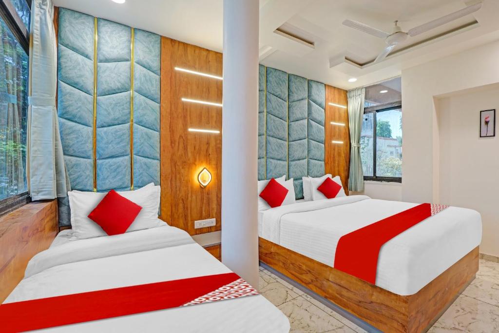 2 bedden in een hotelkamer met rode kussens bij Hotel O Reet Villa in Ahmedabad