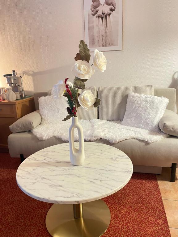 a vase with flowers on a table in a living room at Das CLASSIQUE Galerieappartement 45qm - Elegant und geräumig wohnen - Espressomaschine, Airfryer, ruhiger Balkon, Poseidon Therme im Haus - inkl Parkgarage in Bad Griesbach