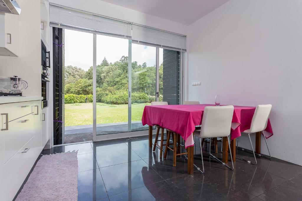 uma sala de jantar com uma mesa rosa e cadeiras em Casa das Camélias - Family Villa by the lagoon em Sete Cidades