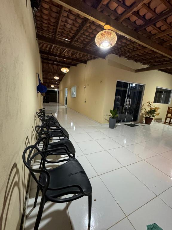 a row of black chairs lined up against a wall at Brisa das dunas in Tutóia
