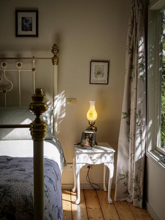 a bedroom with a bed and a table with a lamp at Birdsland Suite in Belgrave Heights