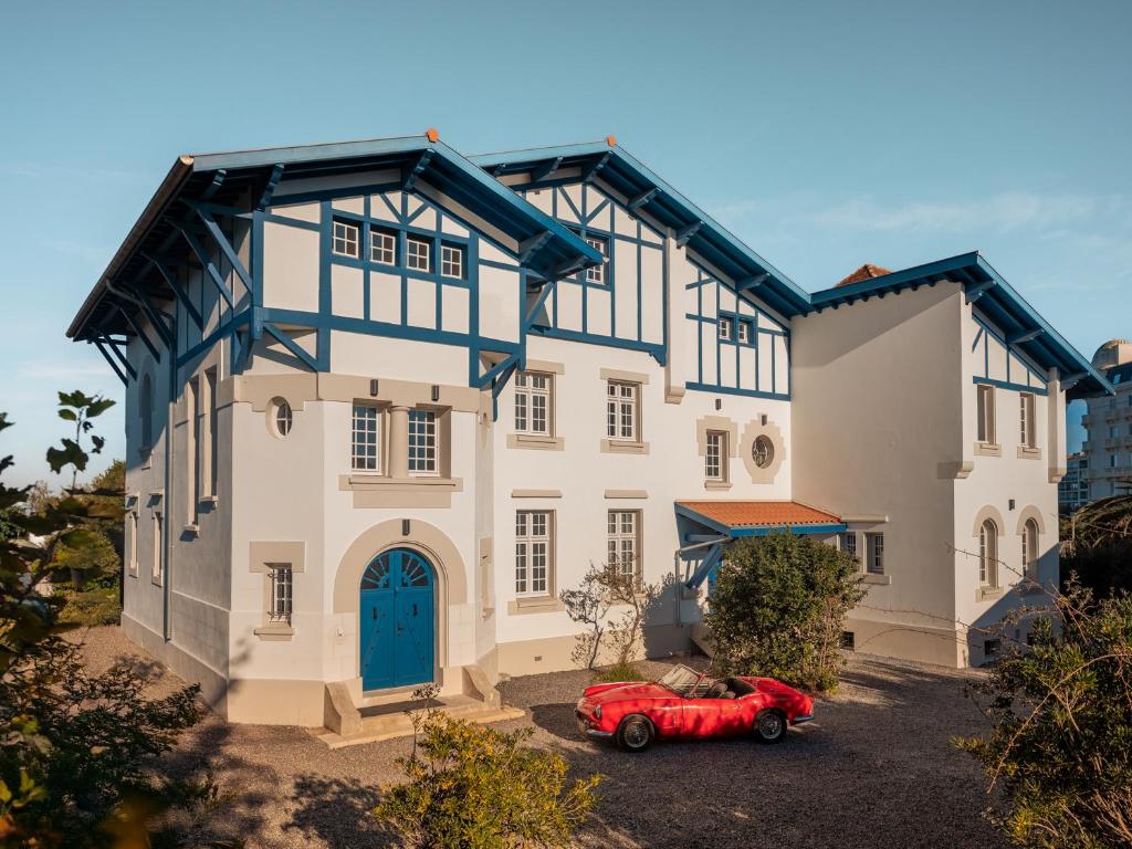 a red car parked in front of a house at Maison Resaurie - Hôtel in Biarritz