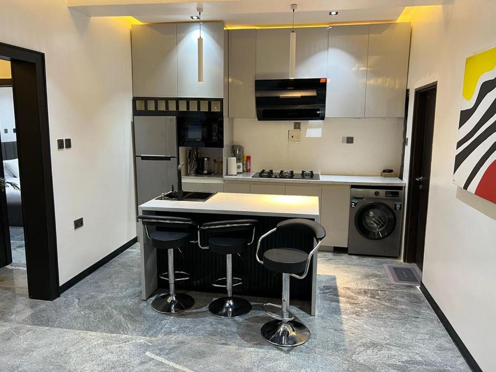 een keuken met een aanrecht en twee barkrukken bij bedandchuckle in Kaduna