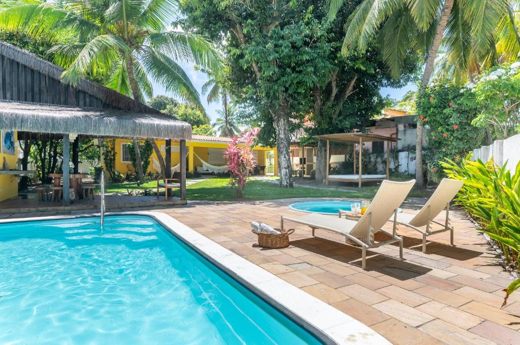 a pool with two lounge chairs next to a house at Casa a 100 metros do mar- no Centro de Porto de Galinhas in Porto De Galinhas