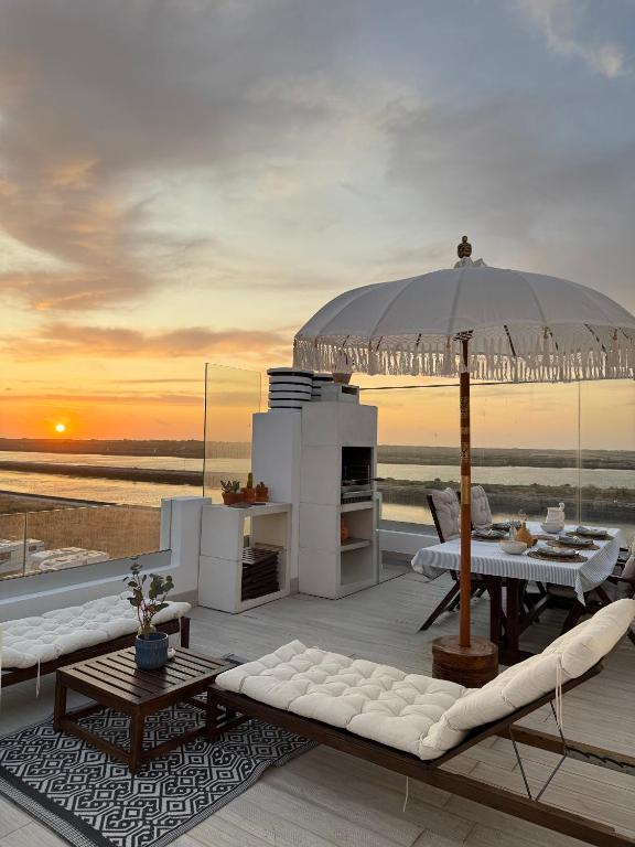 a patio with an umbrella and a table and chairs at Praia da Barra Sweet Home in Gafanha da Nazaré
