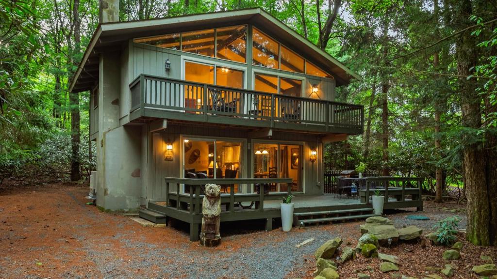a house in the middle of the forest at The Four Seasonal by AvantStay Hot Tub Spacious Deck Fire Pit in Pocono Pines