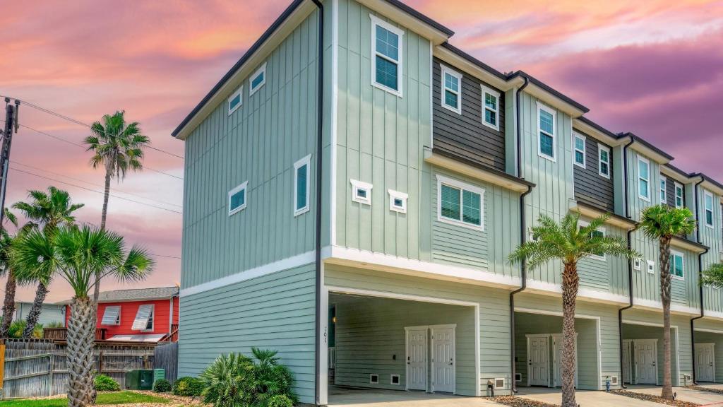 Un gran edificio con palmeras delante. en Saltwater Pool Rooftop Deck w View Near Beach The Blue Crab by AvantStay, en Port Aransas