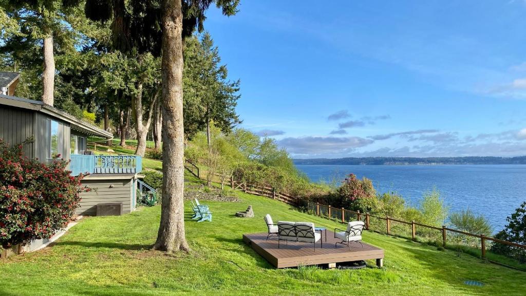 a house with a bench in the grass next to the water at Saratoga by the Sea by AvantStay Panoramic View Near Langley in Langley