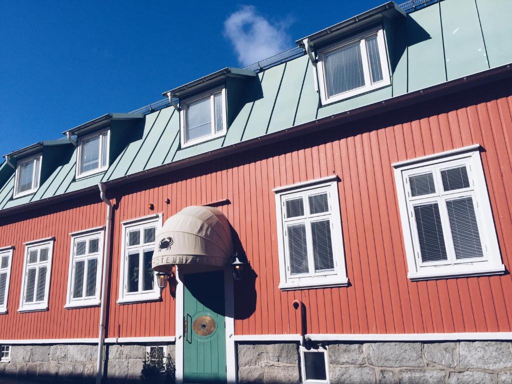 a red building with a green door and windows at Hotell Krabban in Strömstad