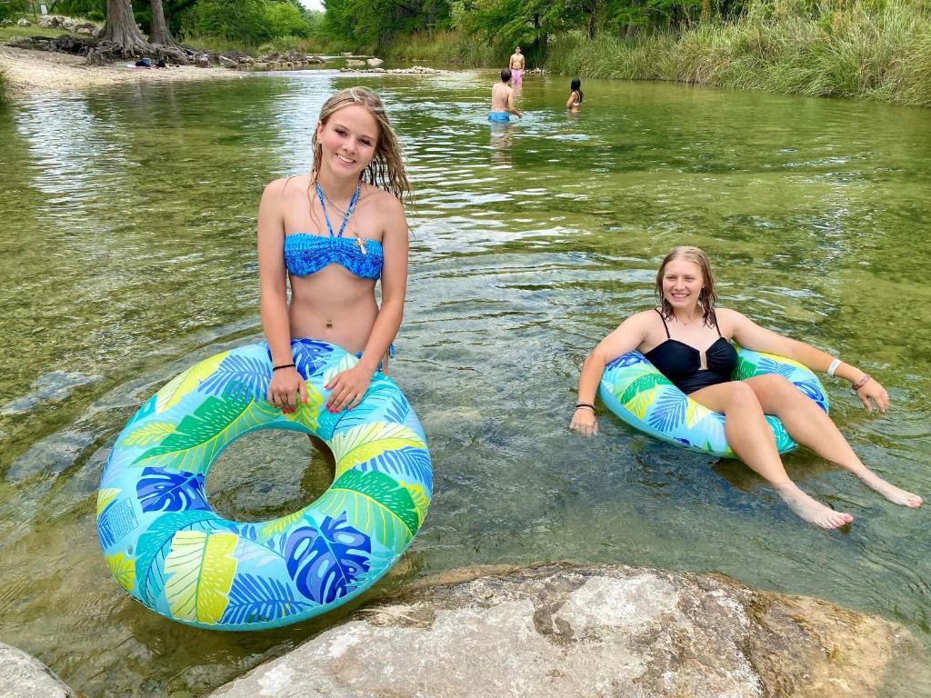 two girls in the water on inflatables in a river at On the Rocks! in Concan