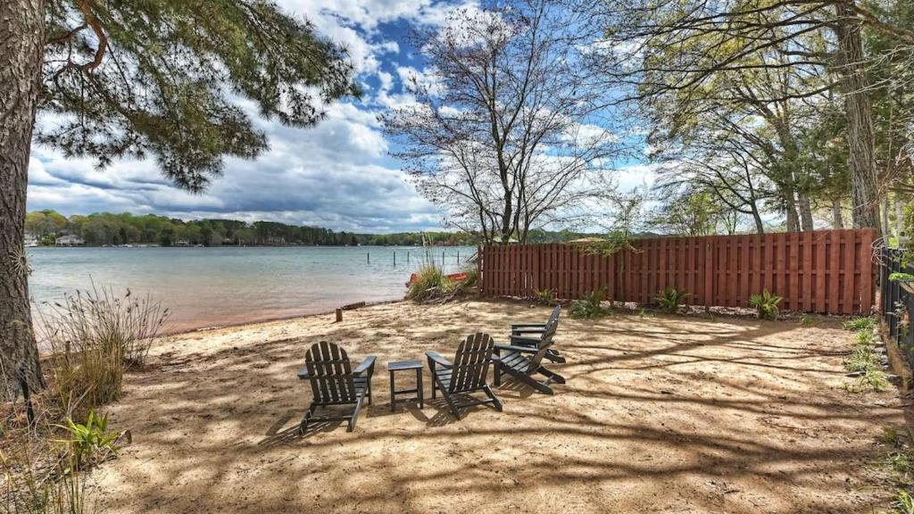 two benches sitting on the sand near the water at Laid Back Lake Life by AvantStay Waterfront View in Mooresville