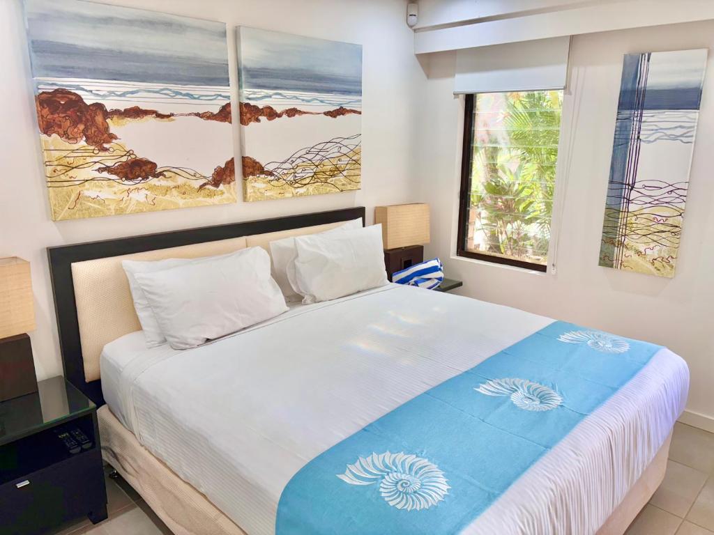 Lagoon Swimout Absolute Pool Front - Tropical Paradise -in Sea Temple Pt Douglas في ميناء دوغلاس: غرفة نوم بسرير كبير عليها لوحتين