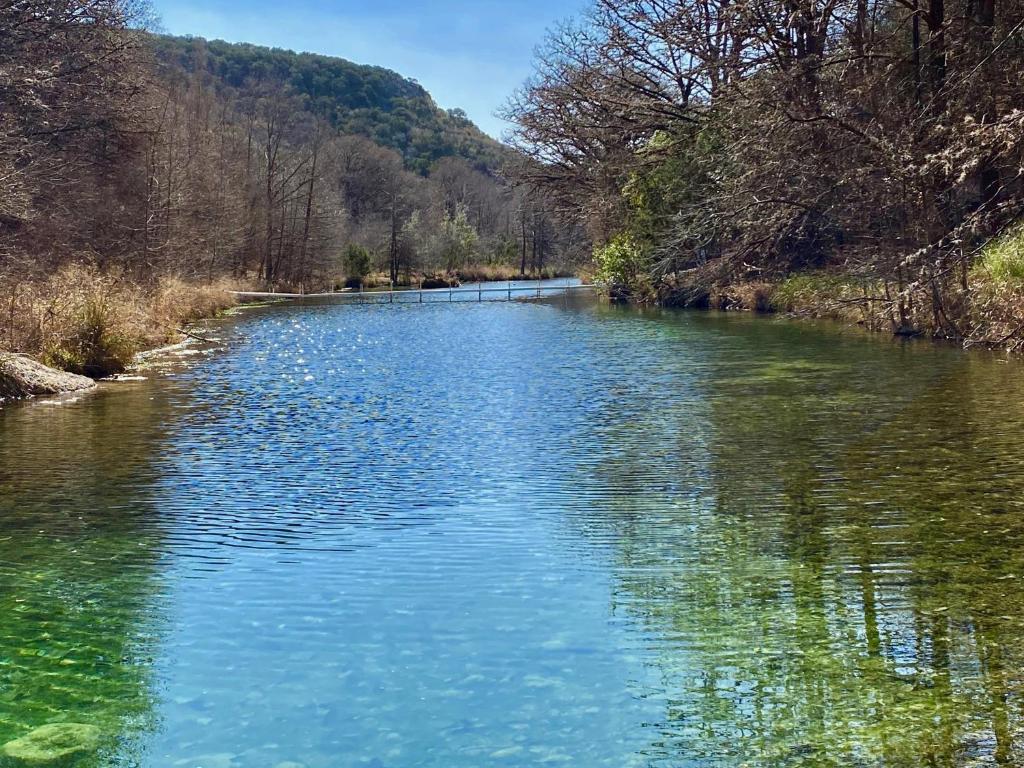 a river with blue water and trees in the background at North Star in Concan