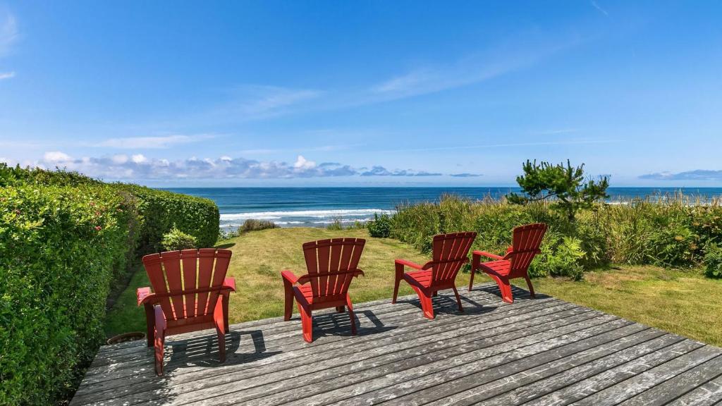a group of four chairs sitting on a deck with the beach at The Pilot House by AvantStay Stunning Home Right On Arch Cape Beach in Arch Cape