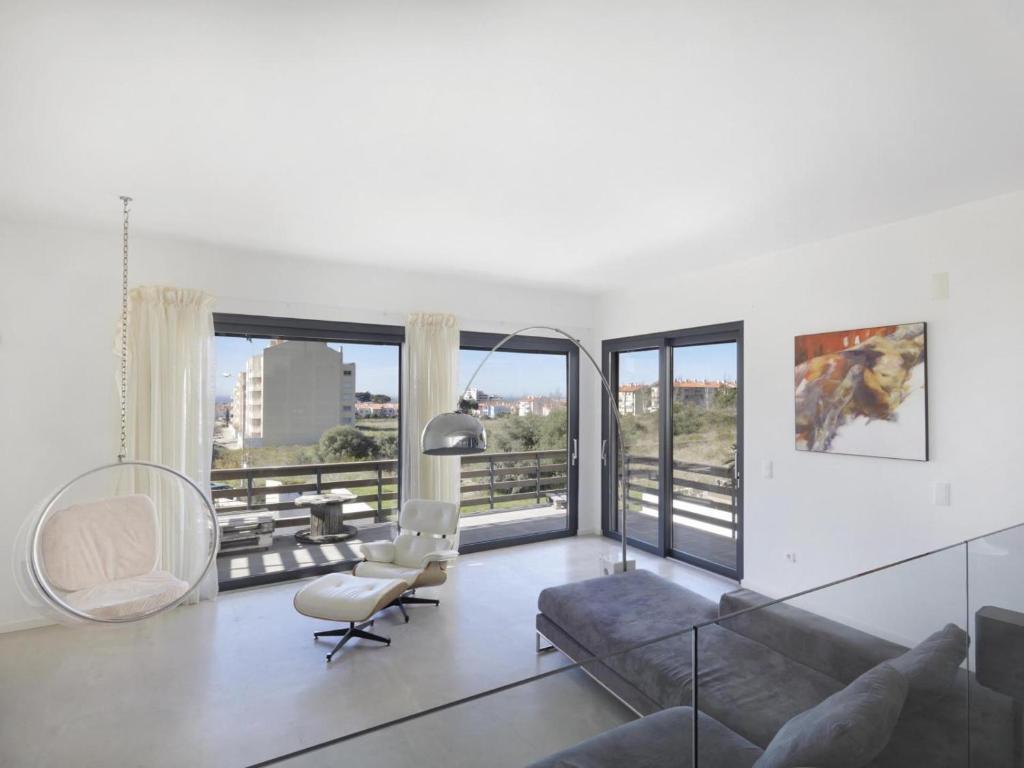 een woonkamer met een bank, stoelen en ramen bij Jardins da Parede Villa in Parede